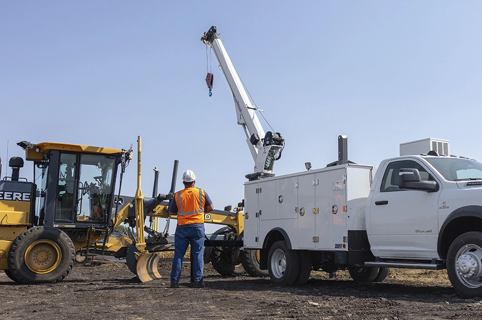 Man standing near TMAX mechanic truck with crane attachment