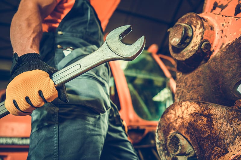 Worker holding a large wrench with a rusted bolt in front of
