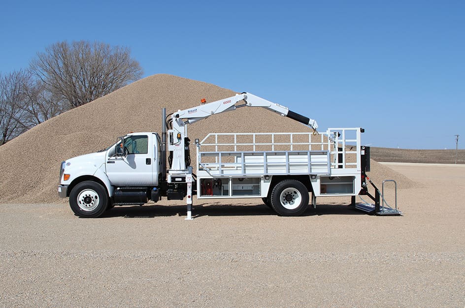 138 Mid-Size OTR Tire Service Truck, left-side view with liftgate dropped to ground and 6000 service crane extended