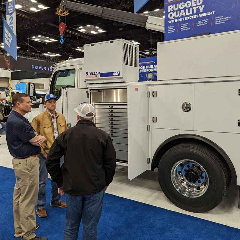 Stellar Rep speaking with visitors in front of a Mechanic Truck showing a 46P compressor and side door opened showing Tool System drawers.