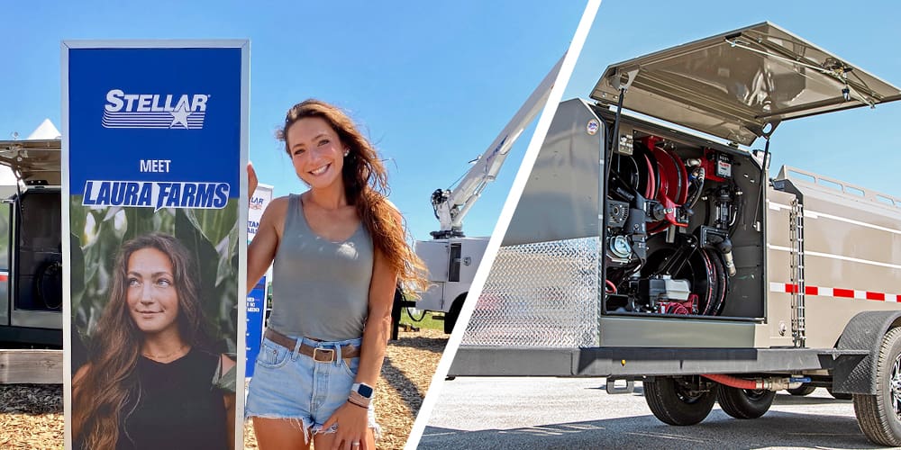 Laura Wilson standing next to a sign with her face and Laura Farms on it and a deluxe fuel trailer on the other side of the image