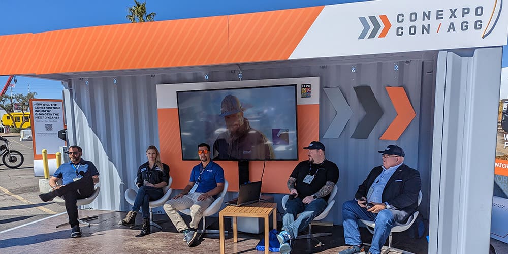 Stellar employees at CONEXPO-CON/AGG under a branded awning and in front of a large television