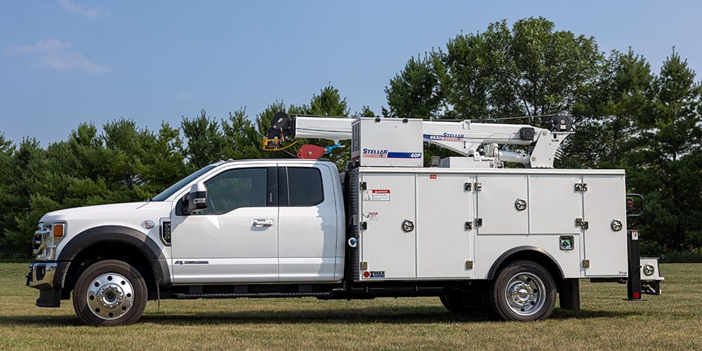 Side view of a Stellar TMAX 1-11 Aluminum Mechanic Truck with 8630 Service Crane and 40P Compressor parked in a field