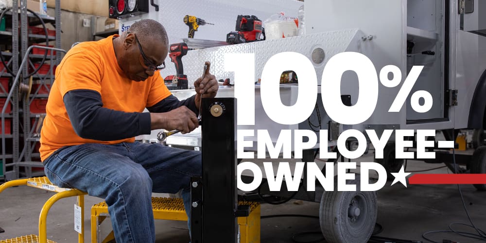 Graphic of 100% employee owned over a photo of a man assembling a mechanic truck.
