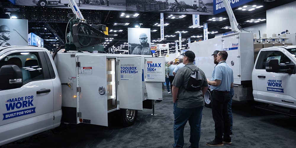 A Stellar trade show scene featuring attendees examining work trucks with open toolboxes.