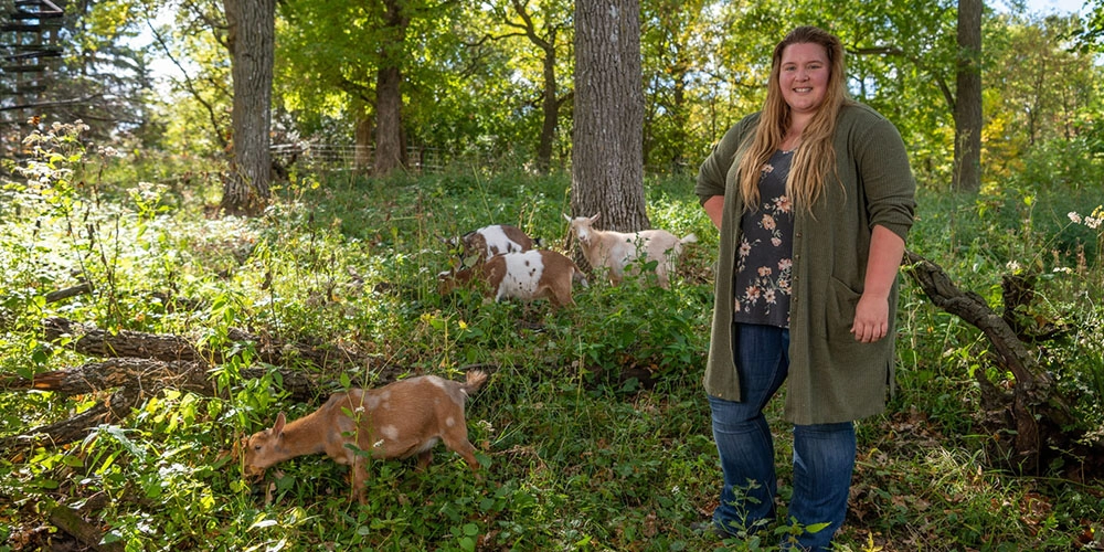 Alex and her goats in the woods.