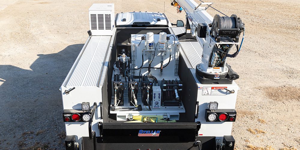 Top-down view of a Stellar Lube Skid with fluid pumps and hose reels mounted in a service truck bed with crane.