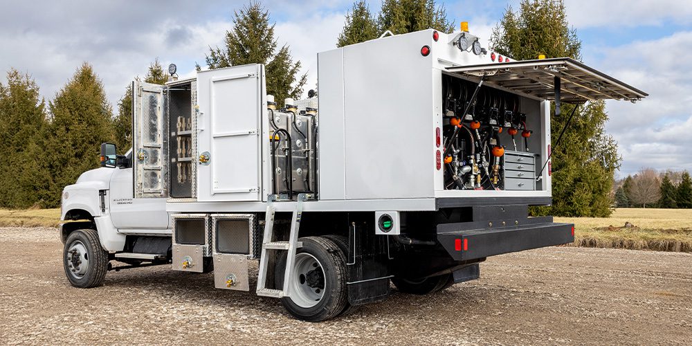 White Stellar Fuel & Lube Truck with open service compartments displaying fluid tanks, hose reels, storage drawers, and access ladder.